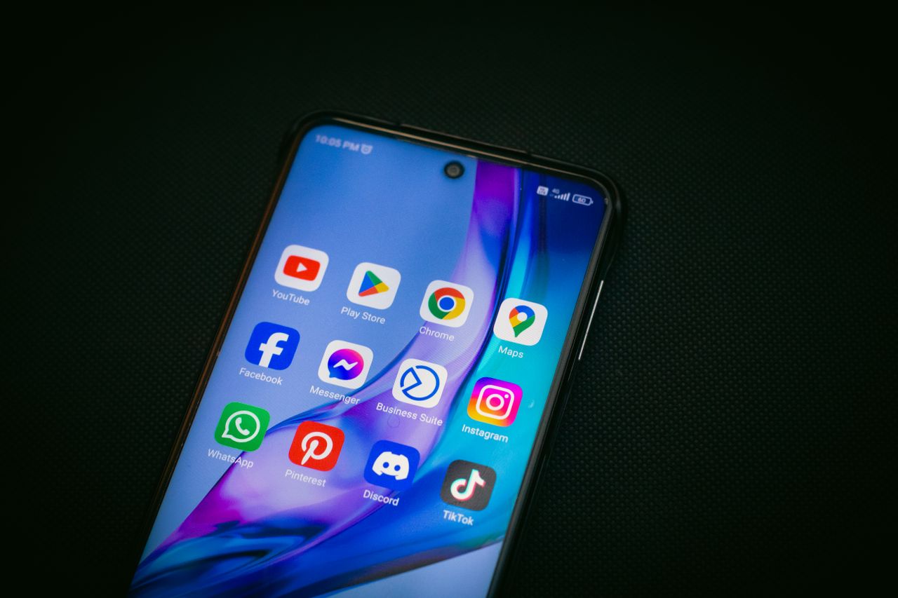 Close-up of a smartphone screen showing popular app icons like YouTube, Maps, and TikTok on a black background.